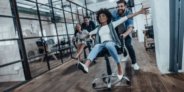 four people in an office playing chair racing