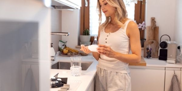 lady in the kitchen pouring out supplement into her hand