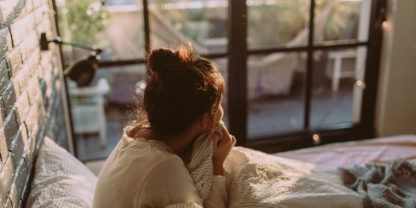 lady sitting in bed looking out the glass doors