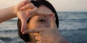 lady by the water creating a square with her fingers and looking through